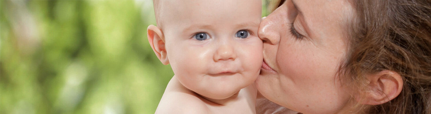 A woman is kissing a baby on the cheek.